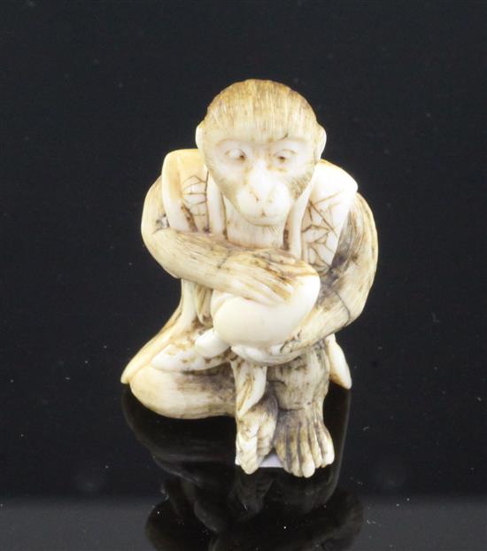 A Japanese ivory netsuke of a seated monkey holding a peach, signed Kogetsu, Meiji period, 3.8cm